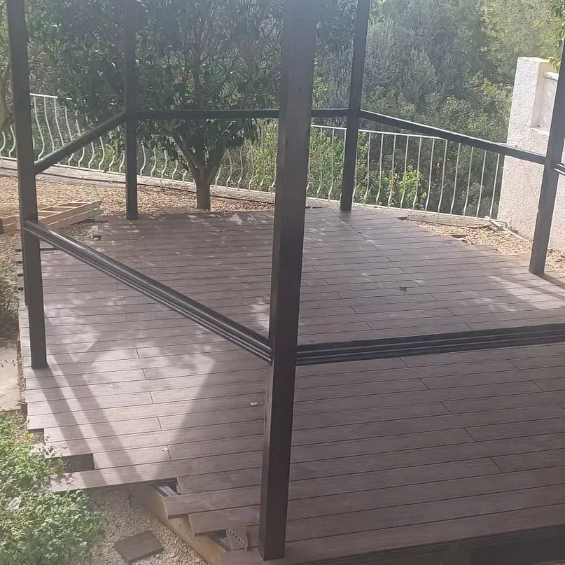 Una terraza de madera con una valla al fondo.