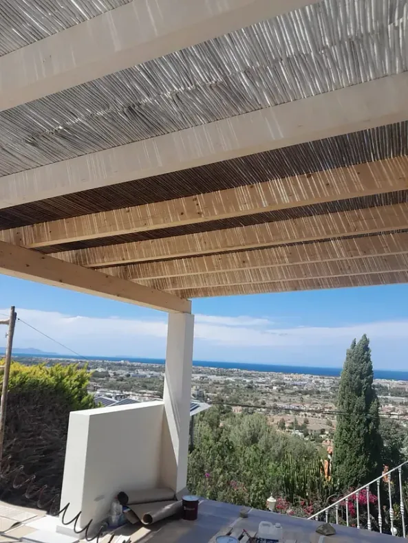 Una pérgola de madera con vista al mar y a la ciudad.