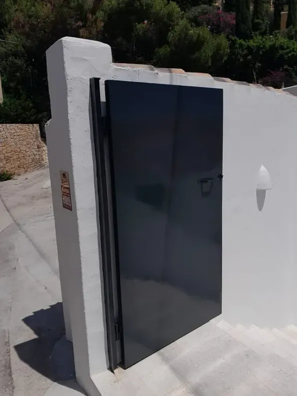 Una puerta negra está abierta en una pared blanca.