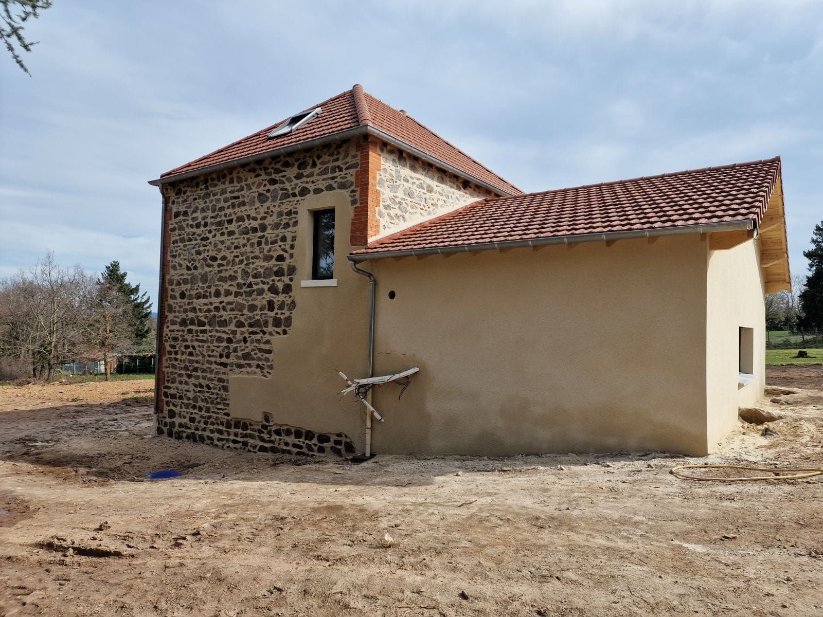 Maiosn avec une façade en crépi et en pierre.