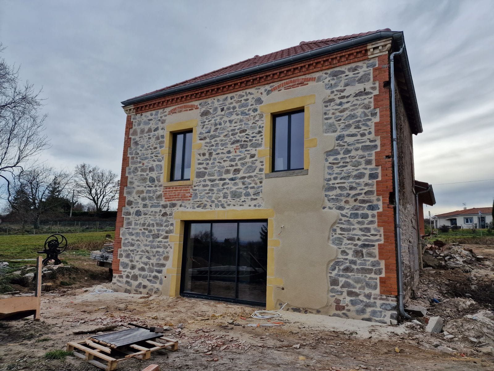 Maison en pierre avec angle en brique et contour de fenêtre rénovés.