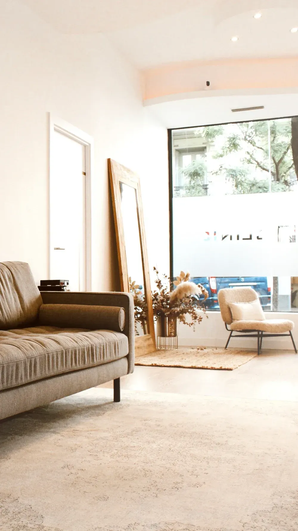 Una sala de estar con un sofá, una silla y un espejo.