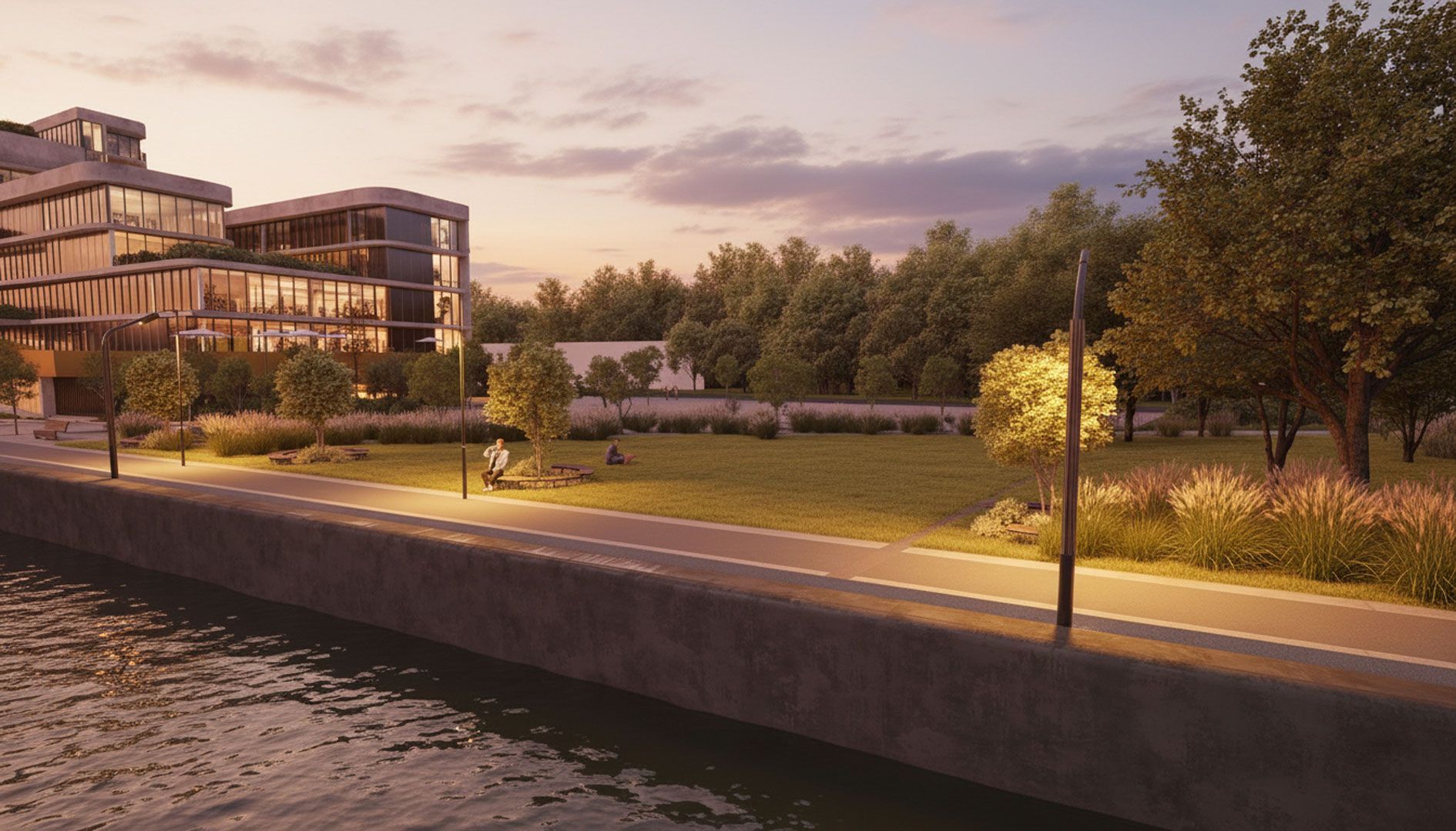 Bâtiment moderne au bord de l'eau, allée éclairée, espace vert, arbres au crépuscule.