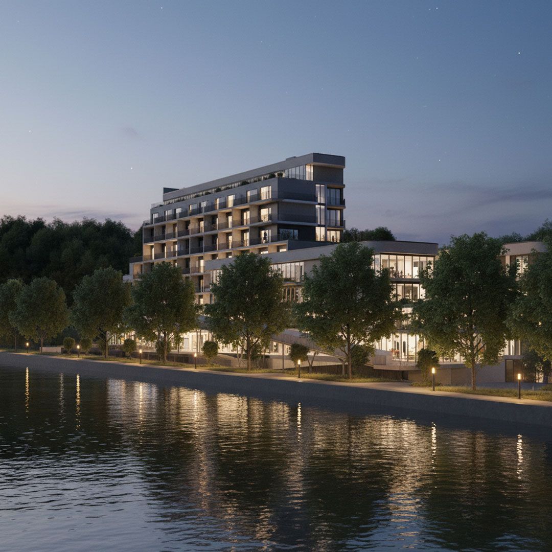 Bâtiment moderne en bord de rivière au crépuscule, les lumières se reflétant sur l'eau. Des arbres bordent la rive.