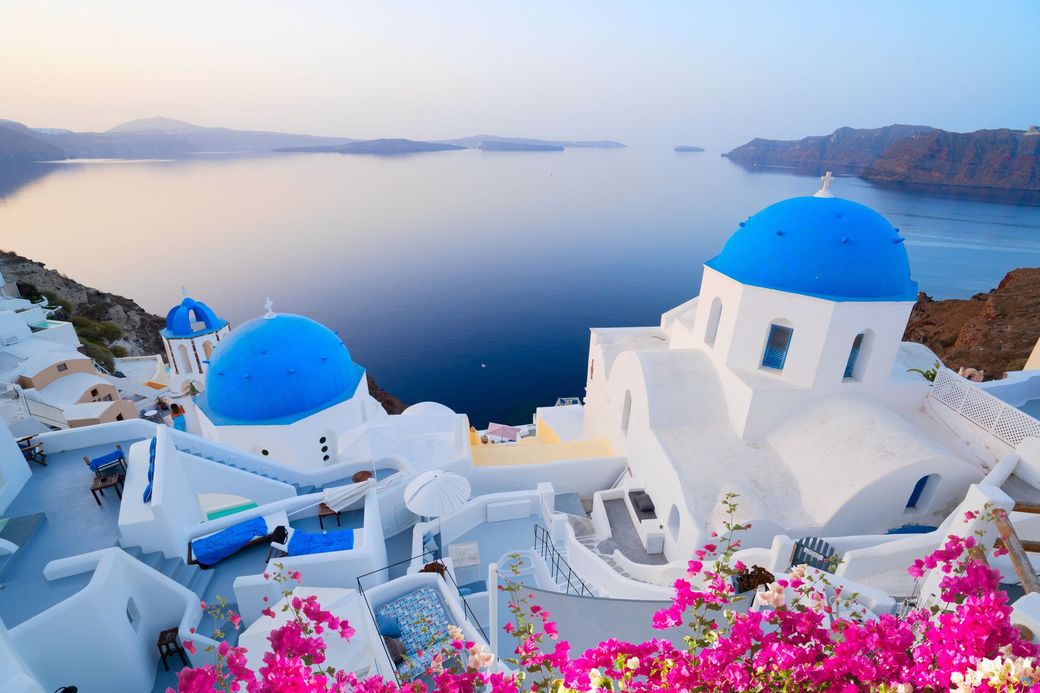 Whitewashed buildings with blue domes overlook the Aegean Sea in Santorini, Greece.