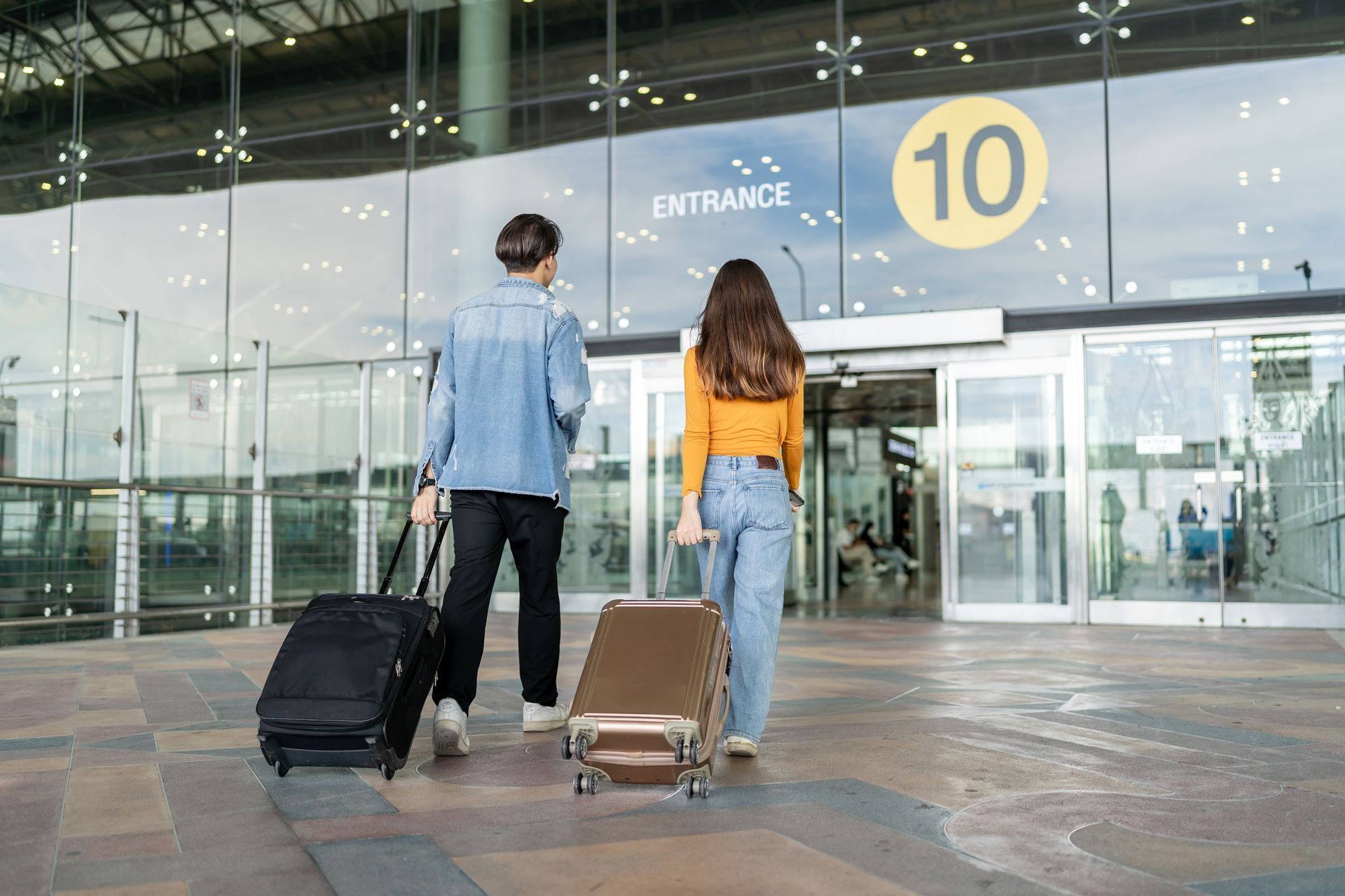 Two people with luggage walk towards airport entrance 10.