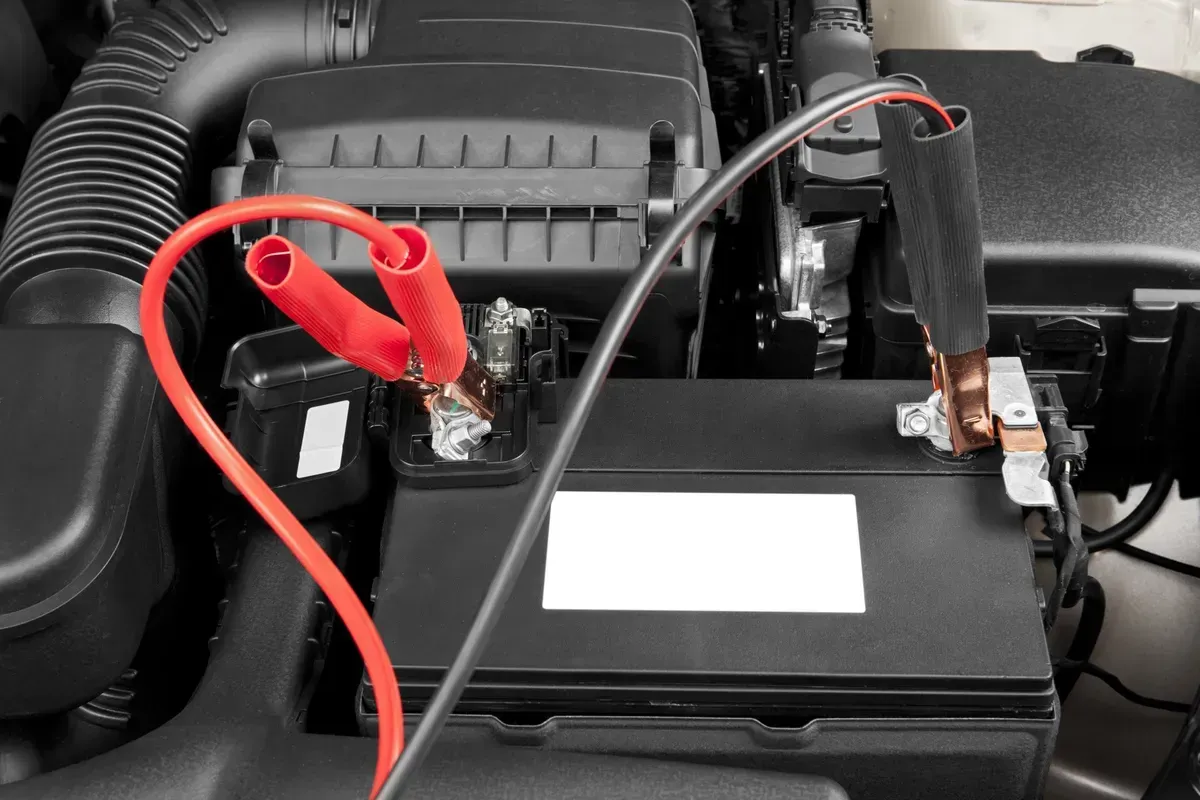 Batterie de voiture avec câbles de démarrage rouges et noirs fixés