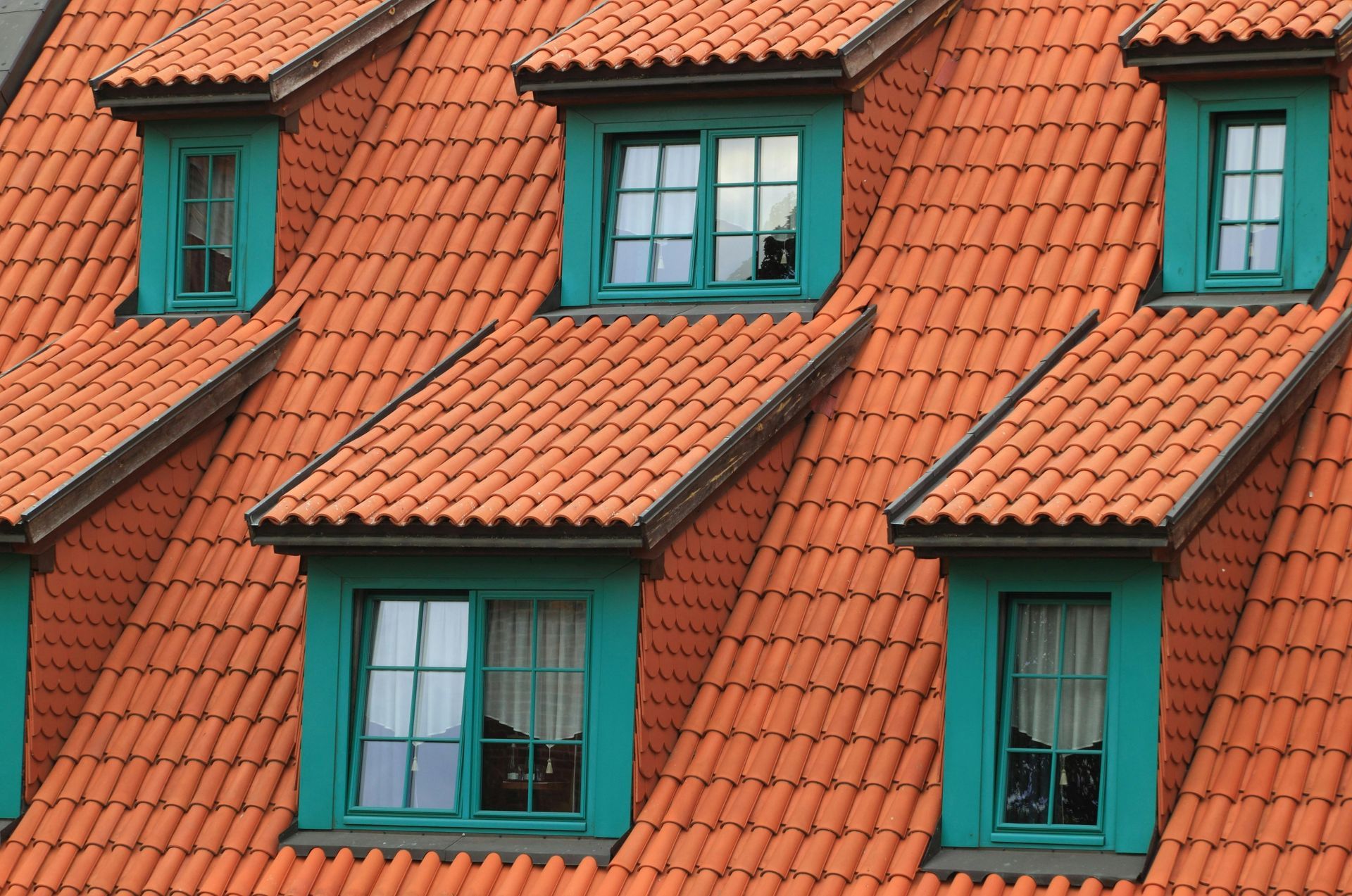 Toit de tuiles rouges avec lucarnes turquoise sur un bâtiment