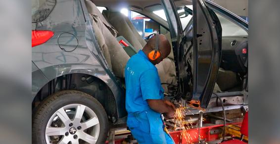 Une personne en bleu en train de réparer une voiture.