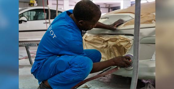 Un homme accroupi à côté d'une voiture.