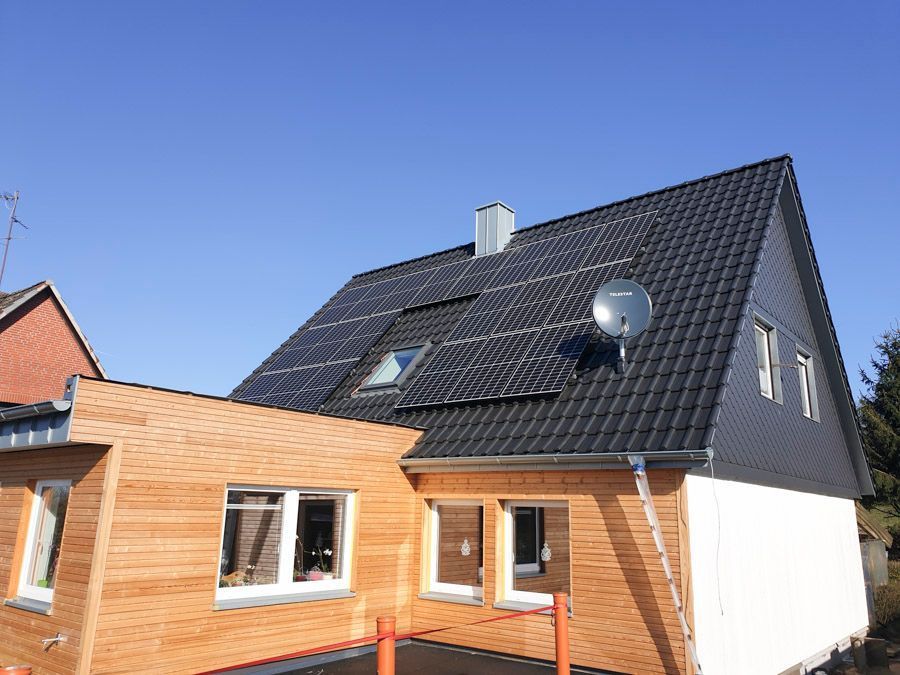 Ein Haus mit einem schwarzen Dach und Solarzellen darauf.