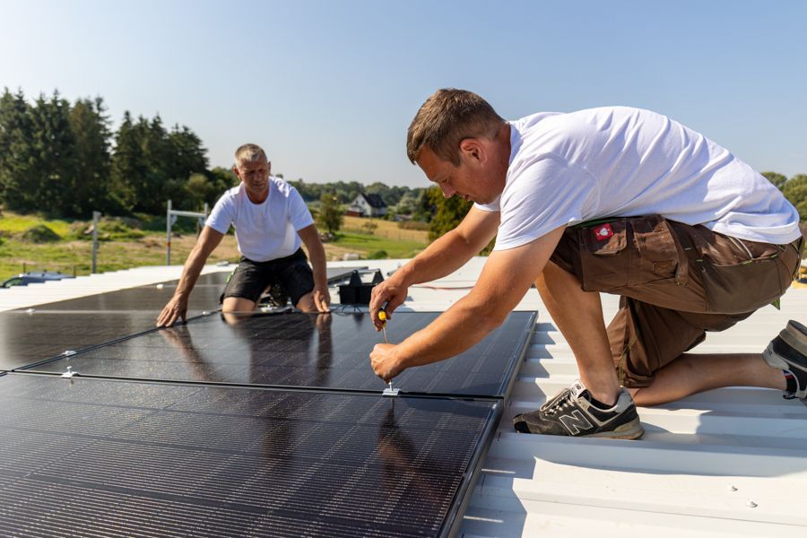 Zwei Männer installieren Solarmodule auf einem Dach.