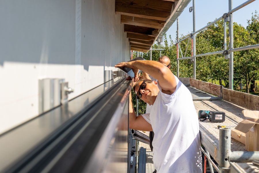 Ein Mann arbeitet an der Seite eines Gebäudes.