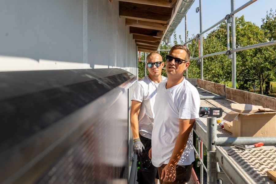 Zwei Männer stehen nebeneinander auf einem Balkon.