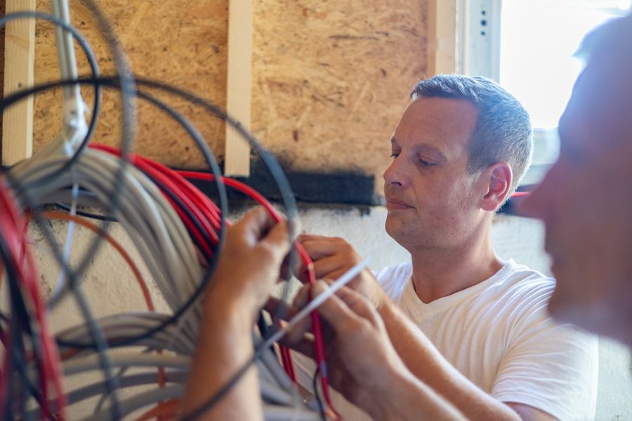 Ein Mann arbeitet in einem Raum an einem Kabelbündel.