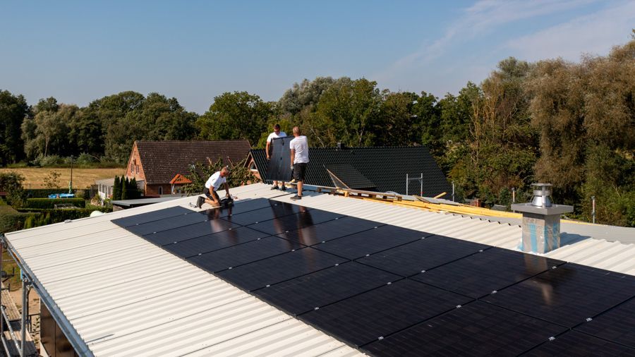 Eine Gruppe von Leuten arbeitet auf einem Dach mit Solarmodulen.