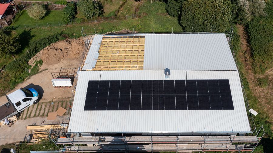 Eine Luftaufnahme eines im Bau befindlichen Hauses mit Solarmodulen auf dem Dach.