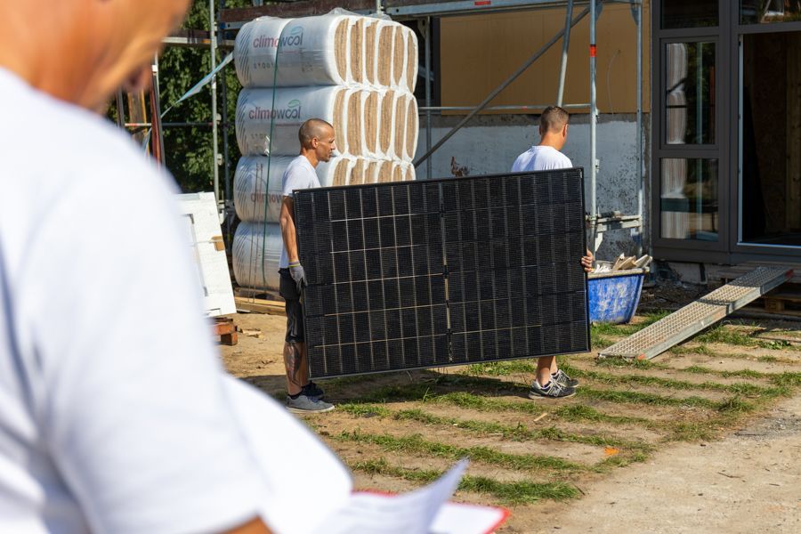 Ein Mann trägt ein großes Solarpanel auf seinem Rücken.