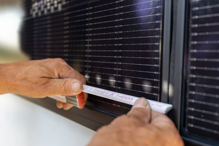 Eine Person misst ein Solarpanel mit einem Lineal.