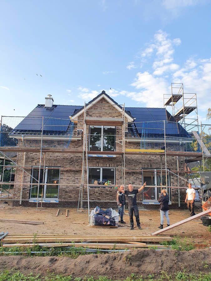 Eine Gruppe von Menschen steht vor einem im Bau befindlichen Haus.