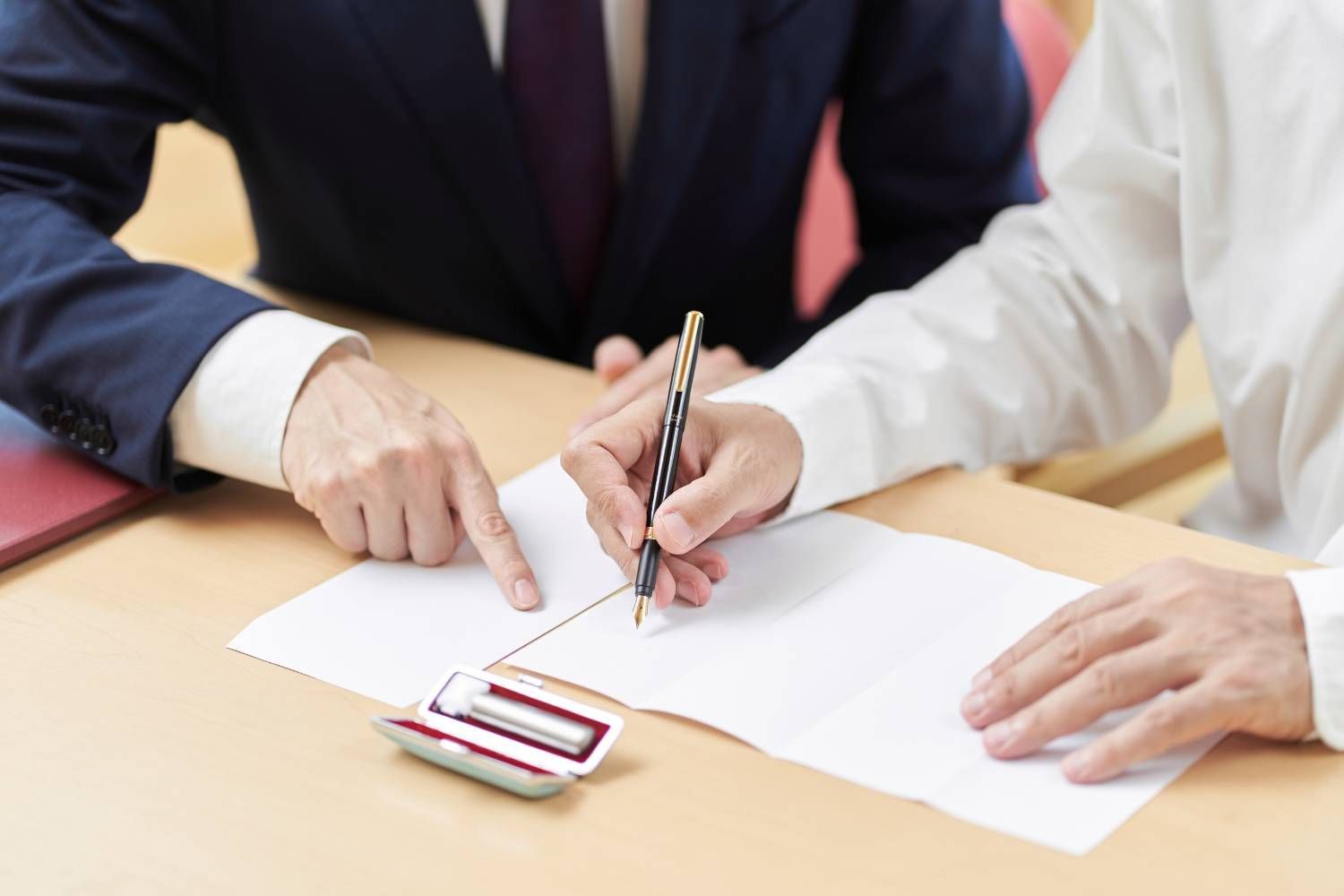 Un hombre y una mujer están sentados en una mesa firmando un documento.