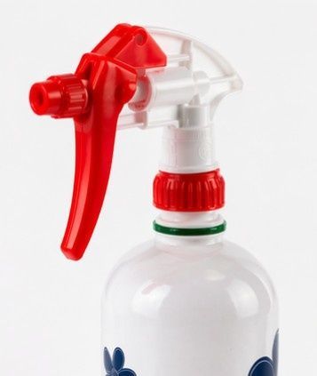 Boquilla pulverizadora roja con gatillo en una botella de plástico blanca con collarín rojo.