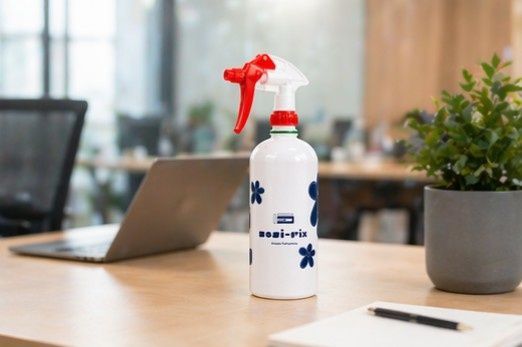 Un pulverizador blanco sobre un escritorio con un portátil y una planta en maceta al fondo.