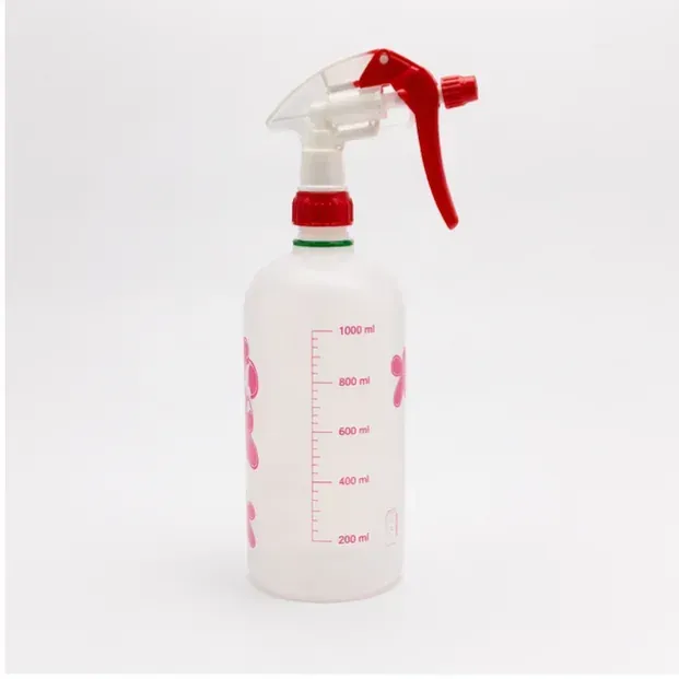 Botella pulverizadora blanca con boquilla de gatillo roja y marcas de medición sobre un fondo liso.