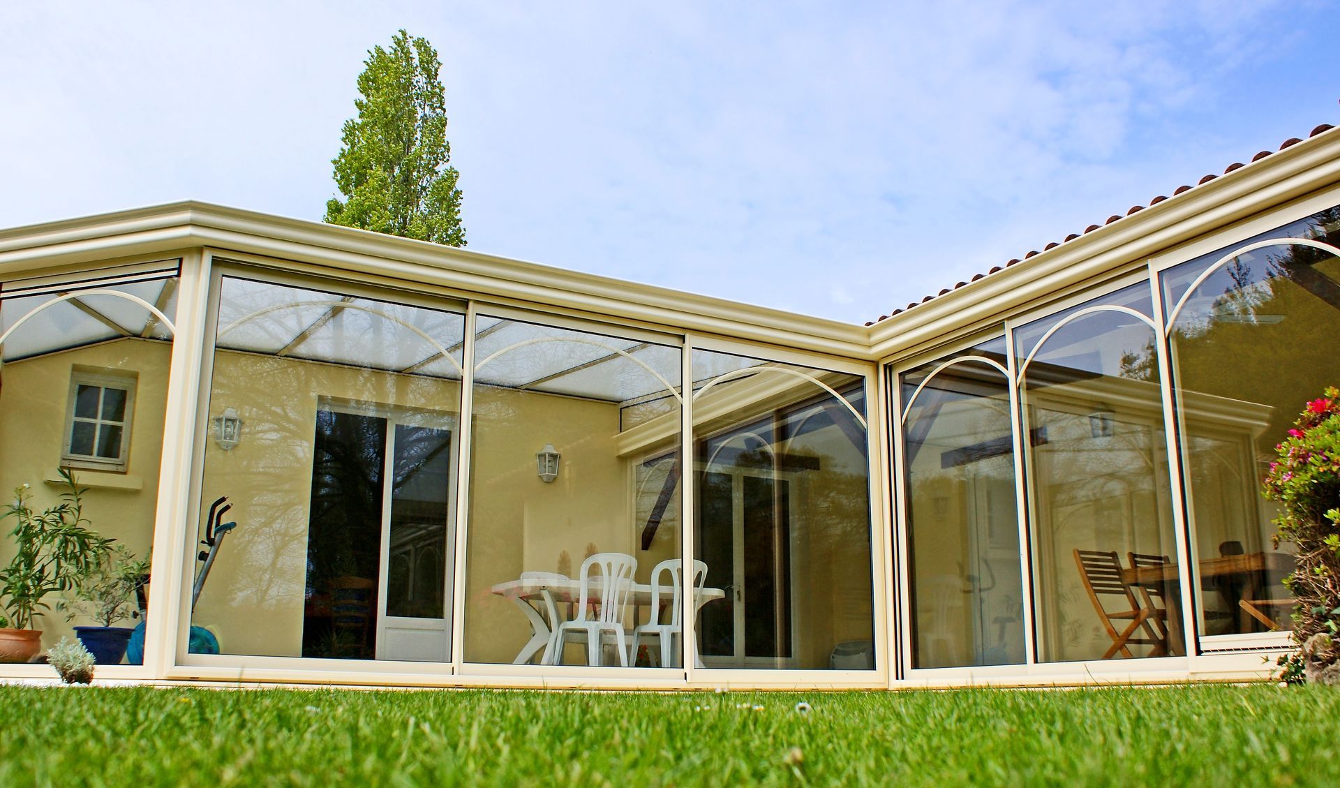 Une véranda en aluminium sur une maison en pierre.
