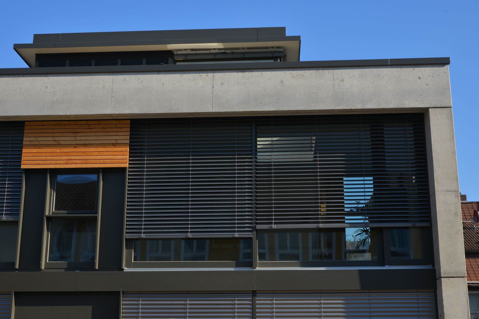 Une façade moderne équipée de brise-soleil orientables en métal.