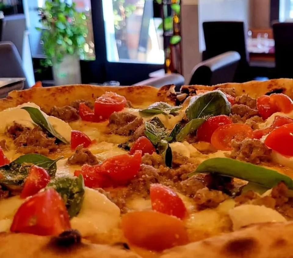 Un gros plan d'une pizza avec des tomates et de la viande dans un restaurant.