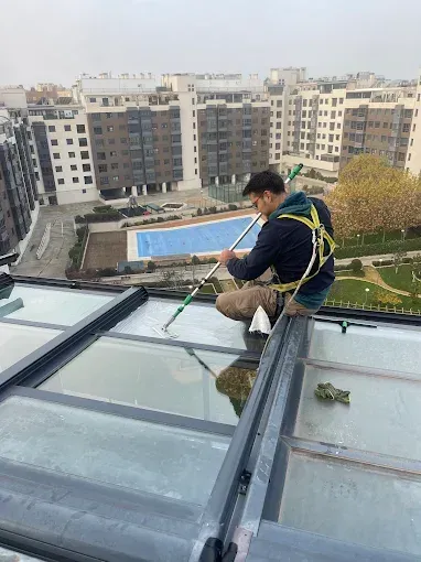 Un trabajador, con arnés de seguridad, limpia una claraboya de cristal
