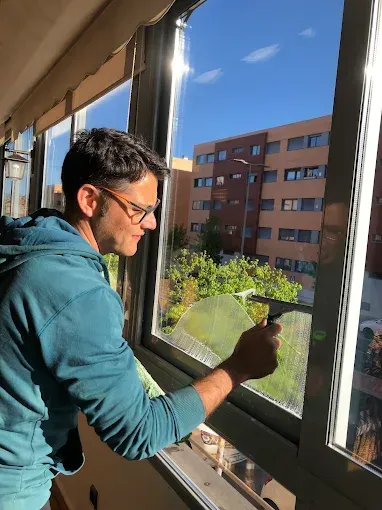 Una persona con una sudadera azul con capucha utiliza una escobilla de goma