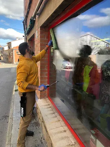 En un día soleado, una persona con una sudadera amarilla con capucha y guantes