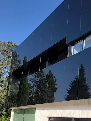 Un edificio moderno con una fachada negra brillante y reflectante que refleja