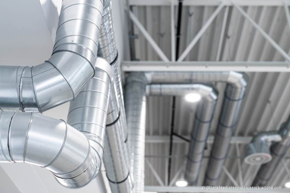 Silberne Lüftungskanäle wurden an einer weißen Decke mit sichtbaren Balken installiert.