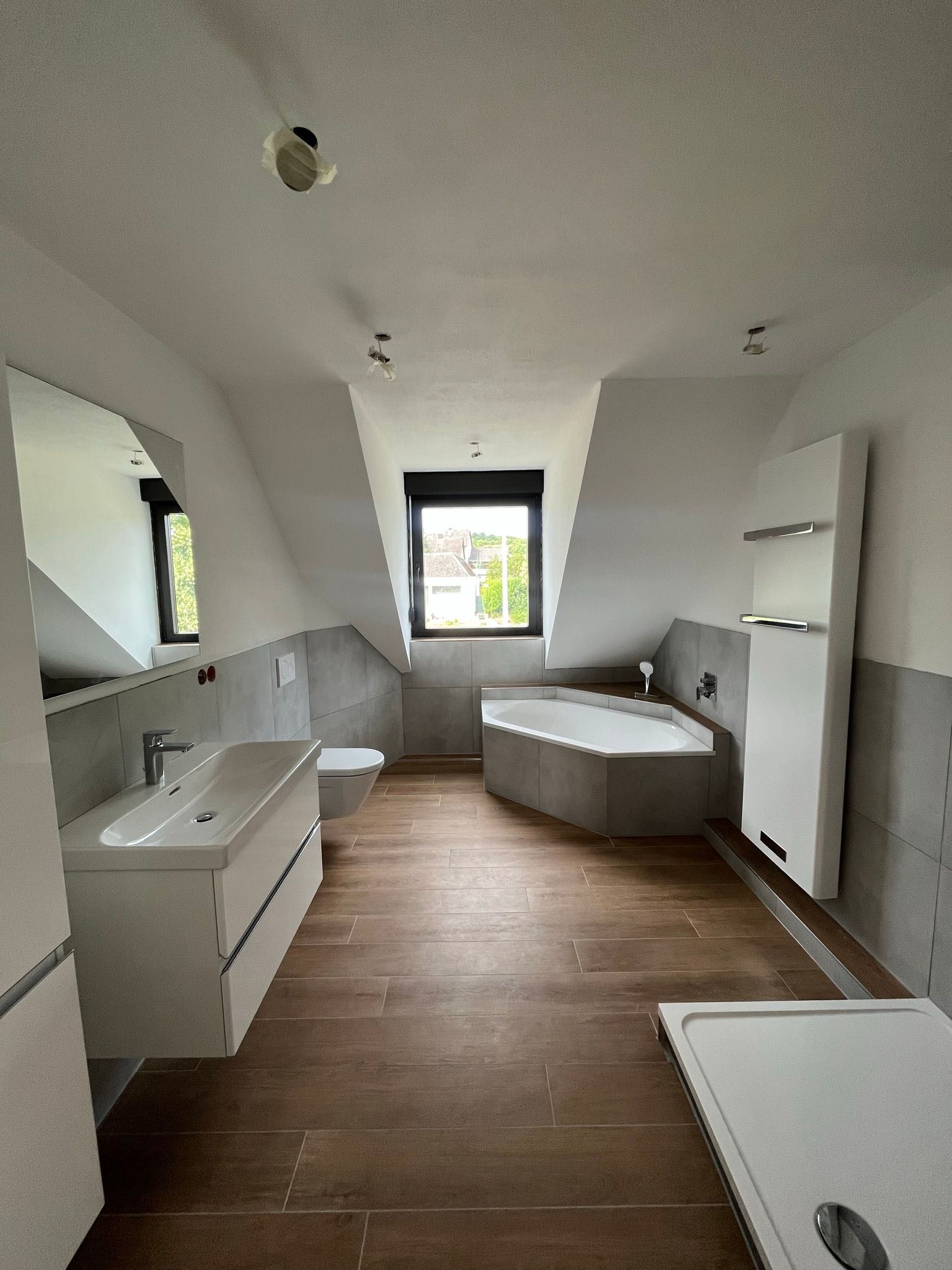 Ein Mann montiert einen Duschkopf in einem Badezimmer; er trägt Handschuhe und einen Werkzeuggürtel.