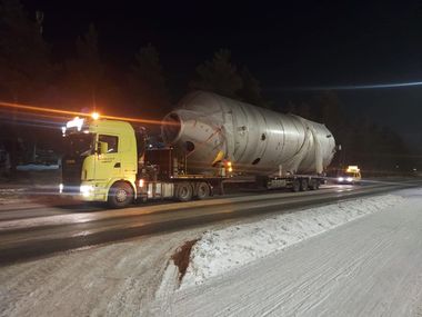 Moderni valkoinen talo mustilla yksityiskohdilla ja puisella terassilla, sininen taivas yläpuolella.