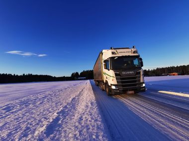 Moderni valkoinen talo mustilla yksityiskohdilla ja puisella terassilla, sininen taivas yläpuolella.
