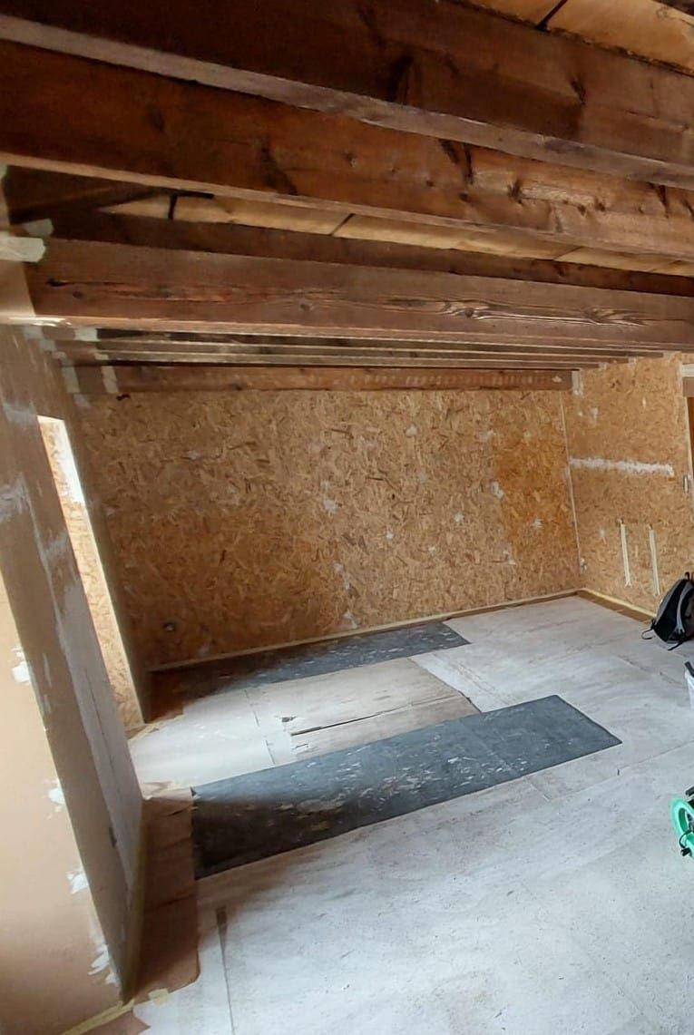 Une pièce avec des poutres en bois et un sol blanc.