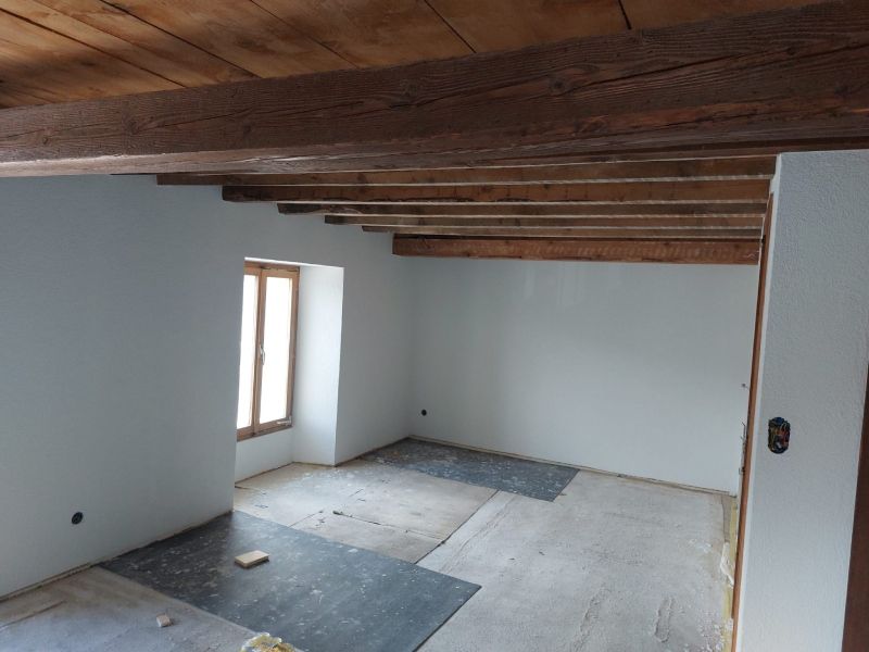 Une pièce avec des murs blancs et des poutres en bois au plafond