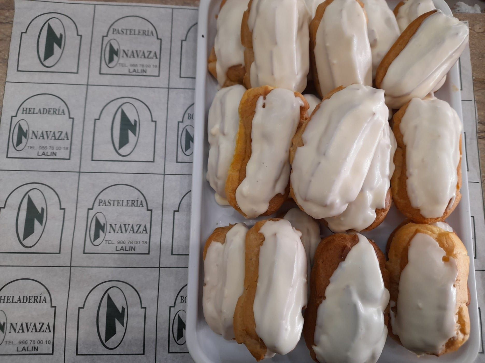 Una bandeja blanca con éclairs rellenos de crema