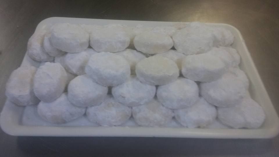 Una bandeja llena de galletas pequeñas y redondas, recubiertas con una generosa capa de azúcar glas blanca.