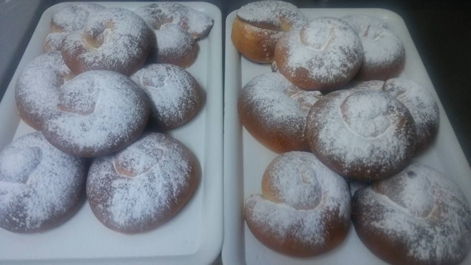 Dos bandejas blancas rectangulares contienen varios pasteles dorados en forma de espiral, espolvoreados con azúcar glas.