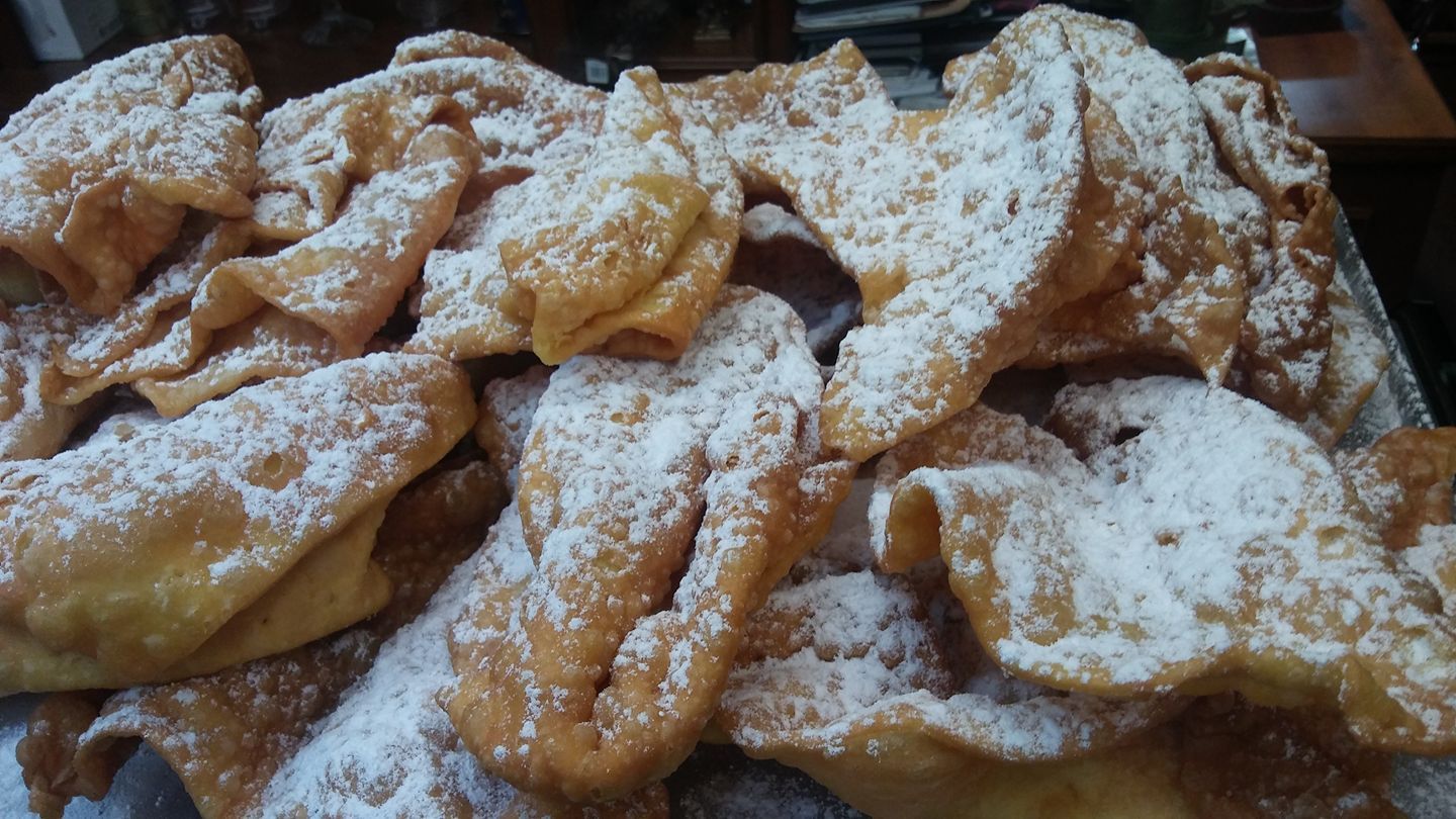 Primer plano de una pila de buñuelos de masa frita de color marrón dorado, generosamente espolvoreados con azúcar glas.