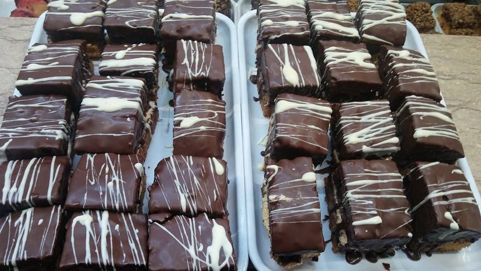 Dos bandejas blancas repletas de filas de brownies cuadrados bañados en glaseado de chocolate blanco.