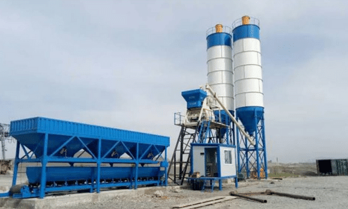 A concrete plant with two silos and a container in a field.