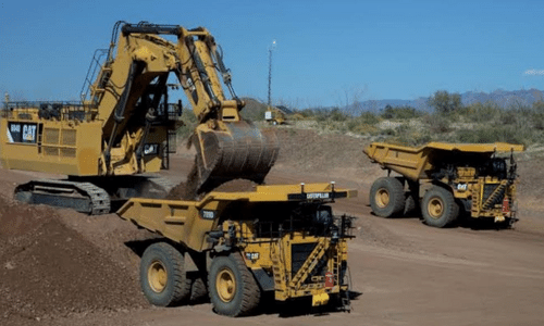 A bulldozer is loading dirt into a dump truck.