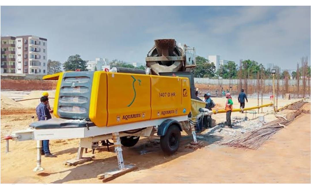 A yellow and white concrete pump is being used on a construction site.