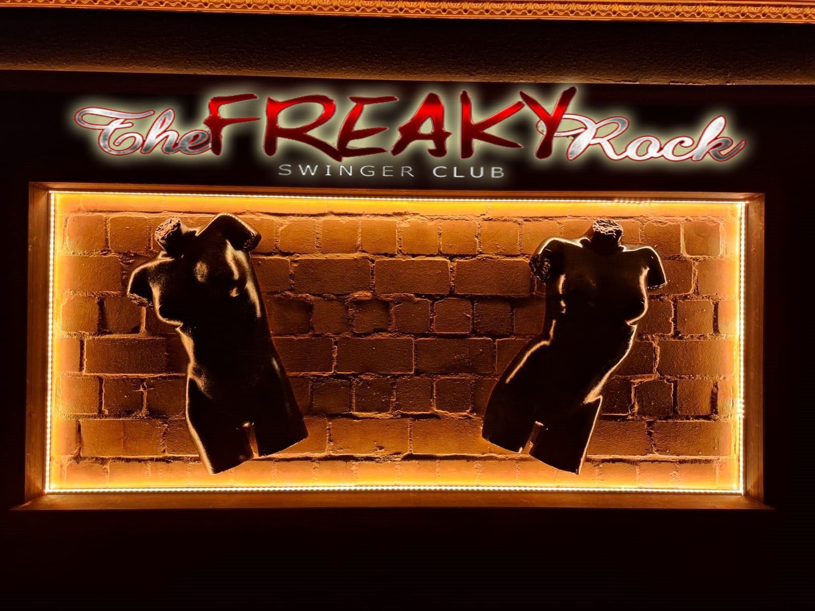 Leuchtreklame für den Nachtclub „Freaky Rock“ mit zwei tanzenden Silhouetten vor einer Backsteinmauer.